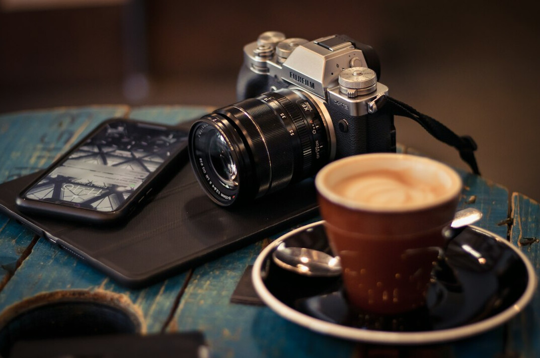 Desk with a camera, notebook and cup of coffee