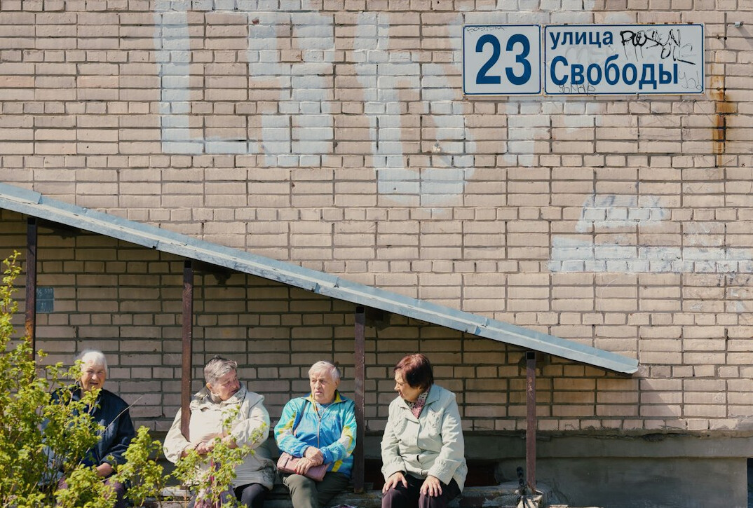 Group of elderly neighbors sitting together outside a building